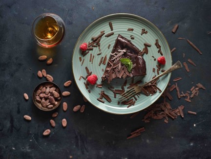 Bohatý čokoládový Čokodort s lákavou vrstvou čokoládové ganache a posypaný čokoládovými hoblinami, představující dokonalost bezlepkového pečení.